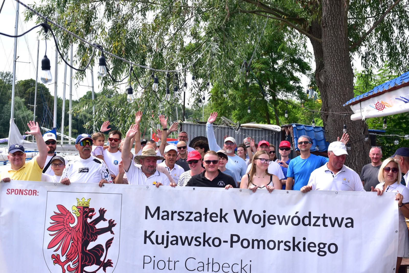 Wspólne zdjęcie grupowe na przystani, na tle żaglówek